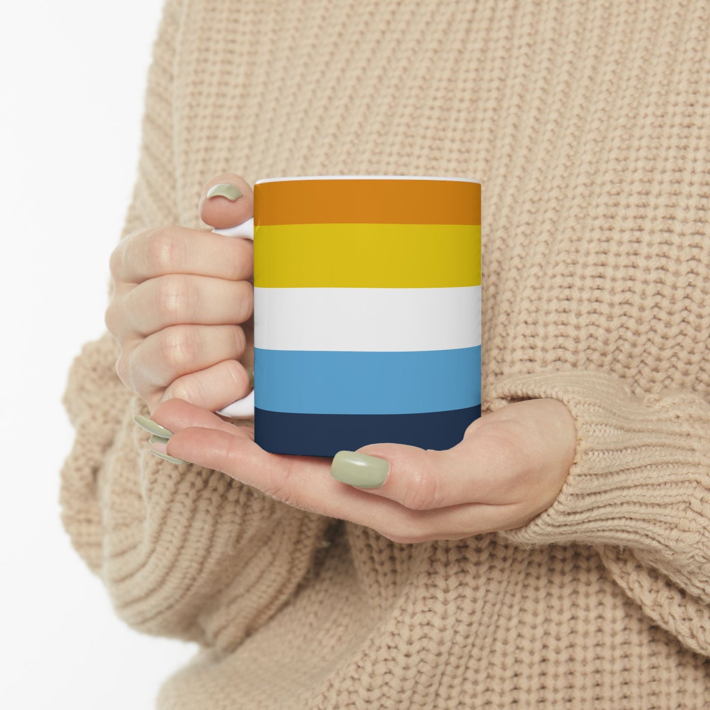 A person in a beige sweater holds the AroAce Pride Flag Mug by WhimSpin in her hands - this ceramic mug has colored striped from top to bottom as follows: orange, yellow/gold, white, blue, and navy 11oz size