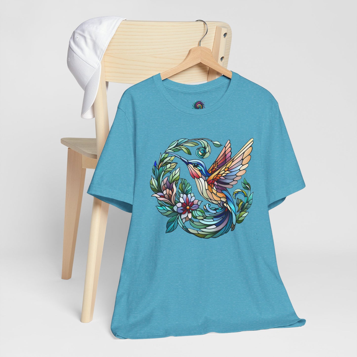 Stained Glass Hummingbird T-Shirt – Colorful Floral Bird Graphic Tee in heather aqua with a stained glass hummingbird and pastel floral styling.