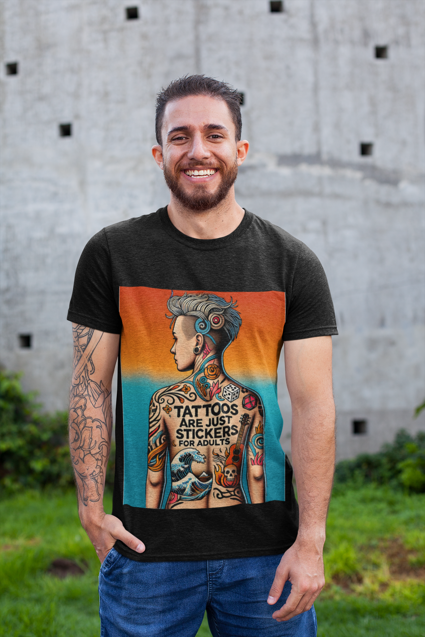 A man with tattoos on his arm wearing a black Tattoos Are Just Stickers For Adults graphic tee from WhimSpin stands outside on grass