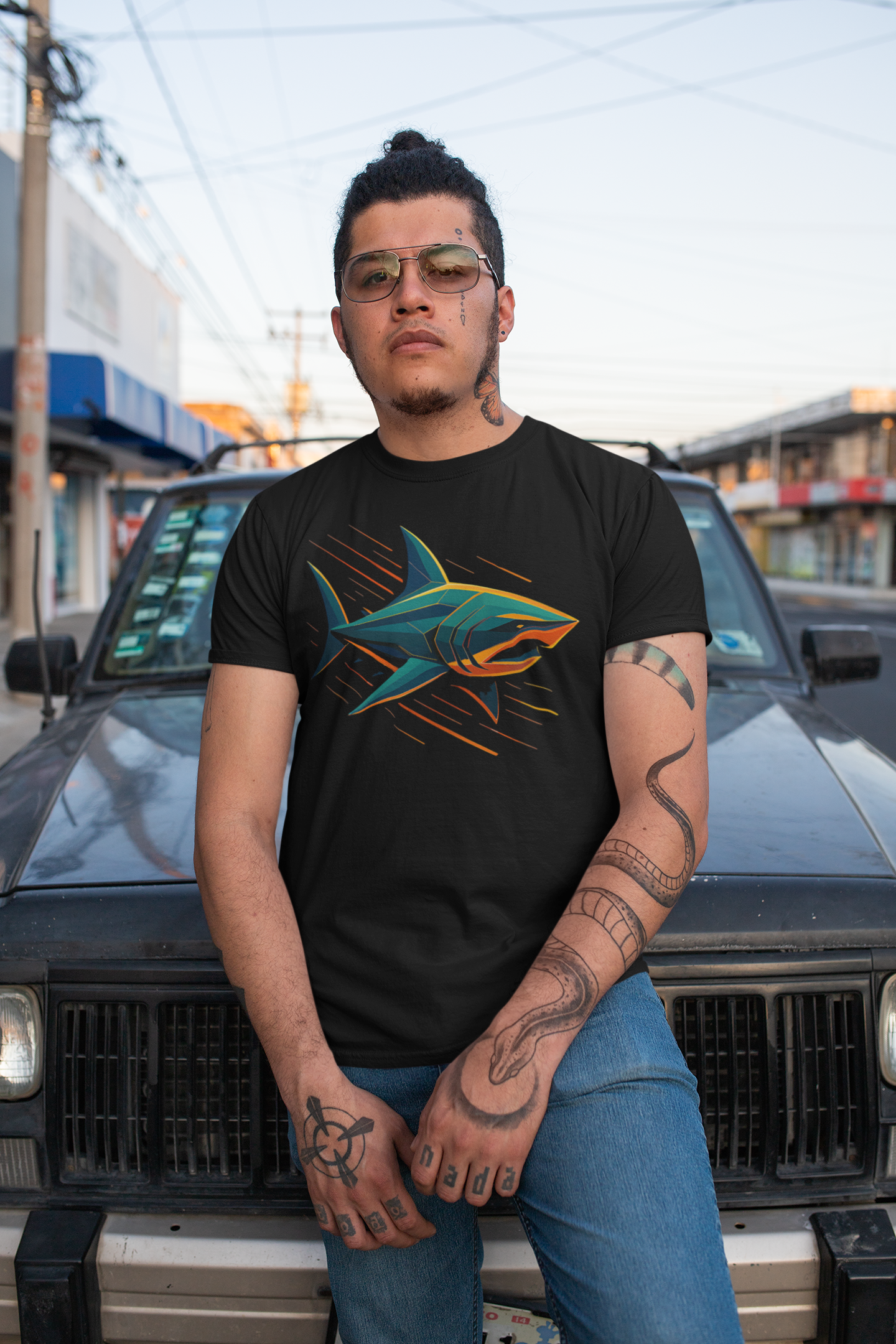 Man sitting on the hood of a car with tattoos on his arms wearing Electric Apex Shark T-Shirt – Bold Ocean Graphic Tee