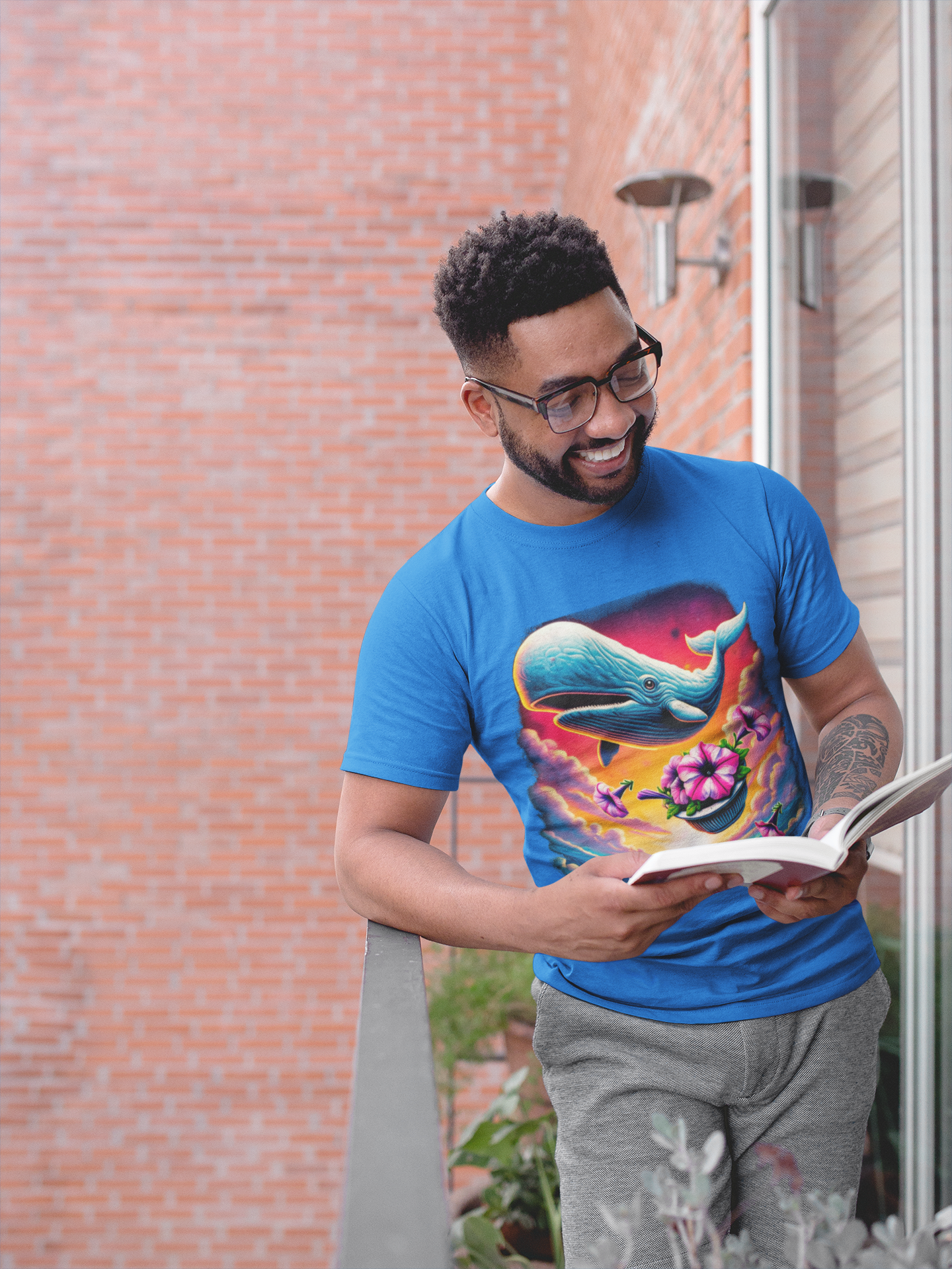 Man reading on balcony in whale shirt "Oh No Not Again" Petunias and Whale Tee – funny Hitchhiker's Guide shirt with floating whale and petunias, perfect for readers, sci-fi fans, and quirky graphic tee collectors