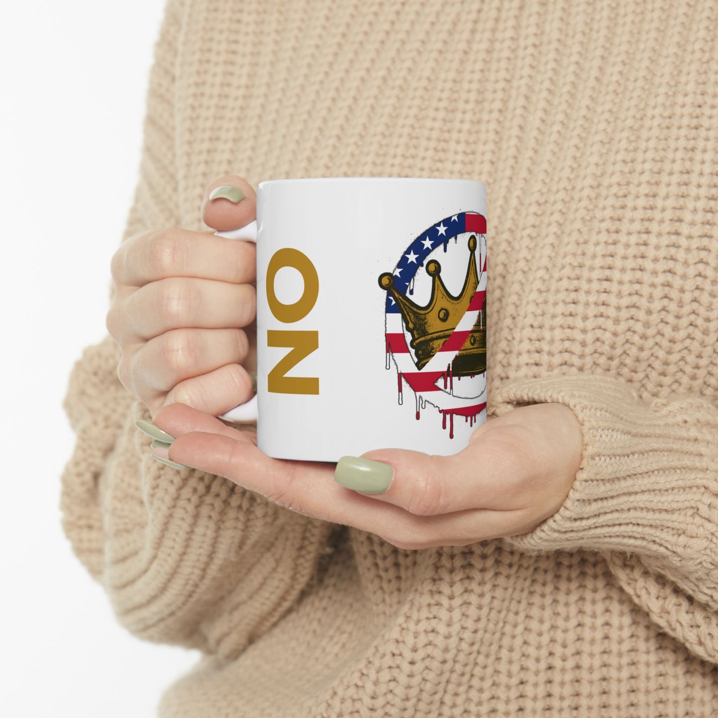 No Kings Mug – Anti-Monarchy Coffee Cup featuring the bold “NO” text and dripping crown, held close-up in two hands, sweater sleeves visible in cozy defiance.