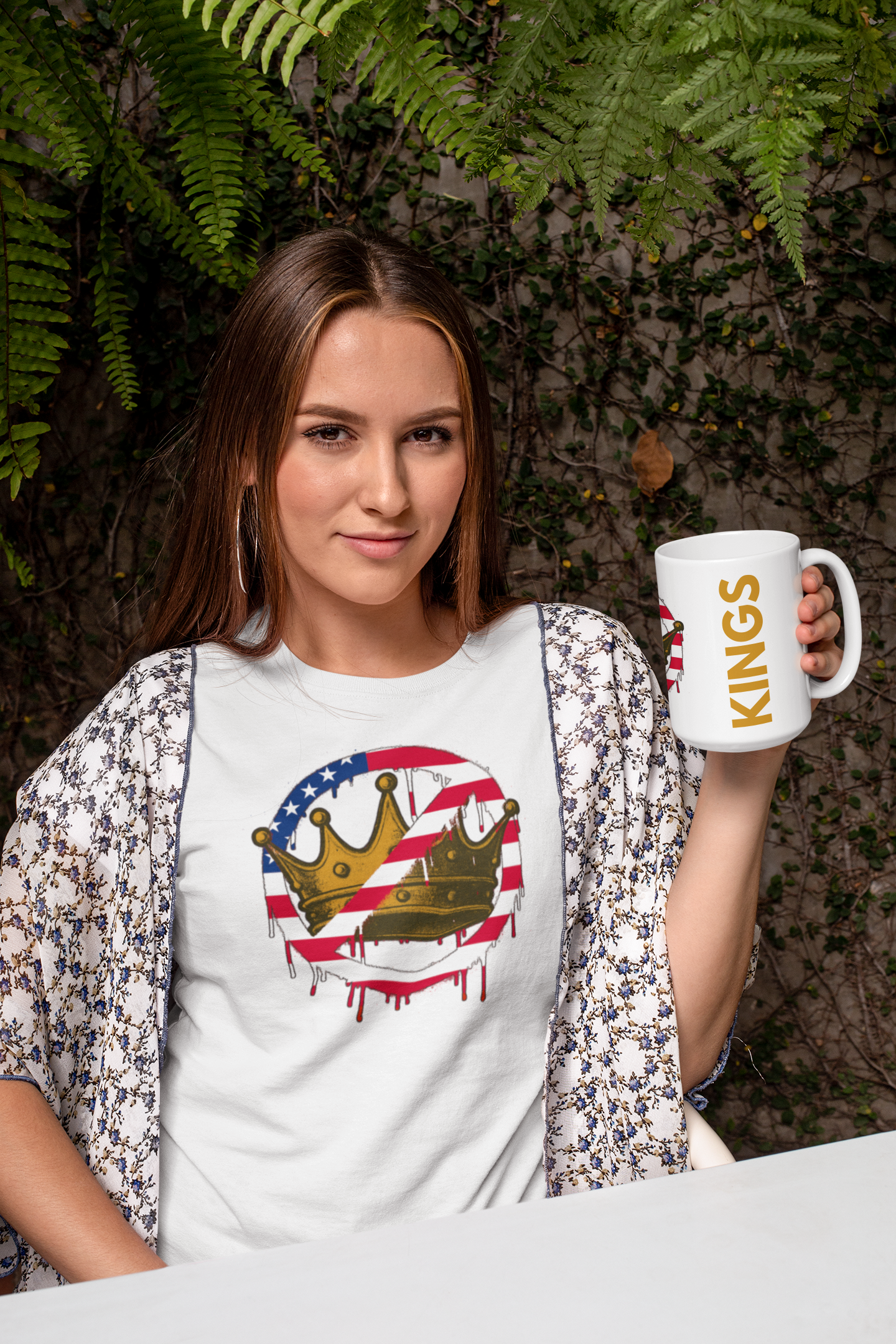 No Kings Mug – Anti-Monarchy Coffee Cup held with the “KINGS” side showing by a woman in a patterned shirt, paired with the matching rebellious graphic tee.