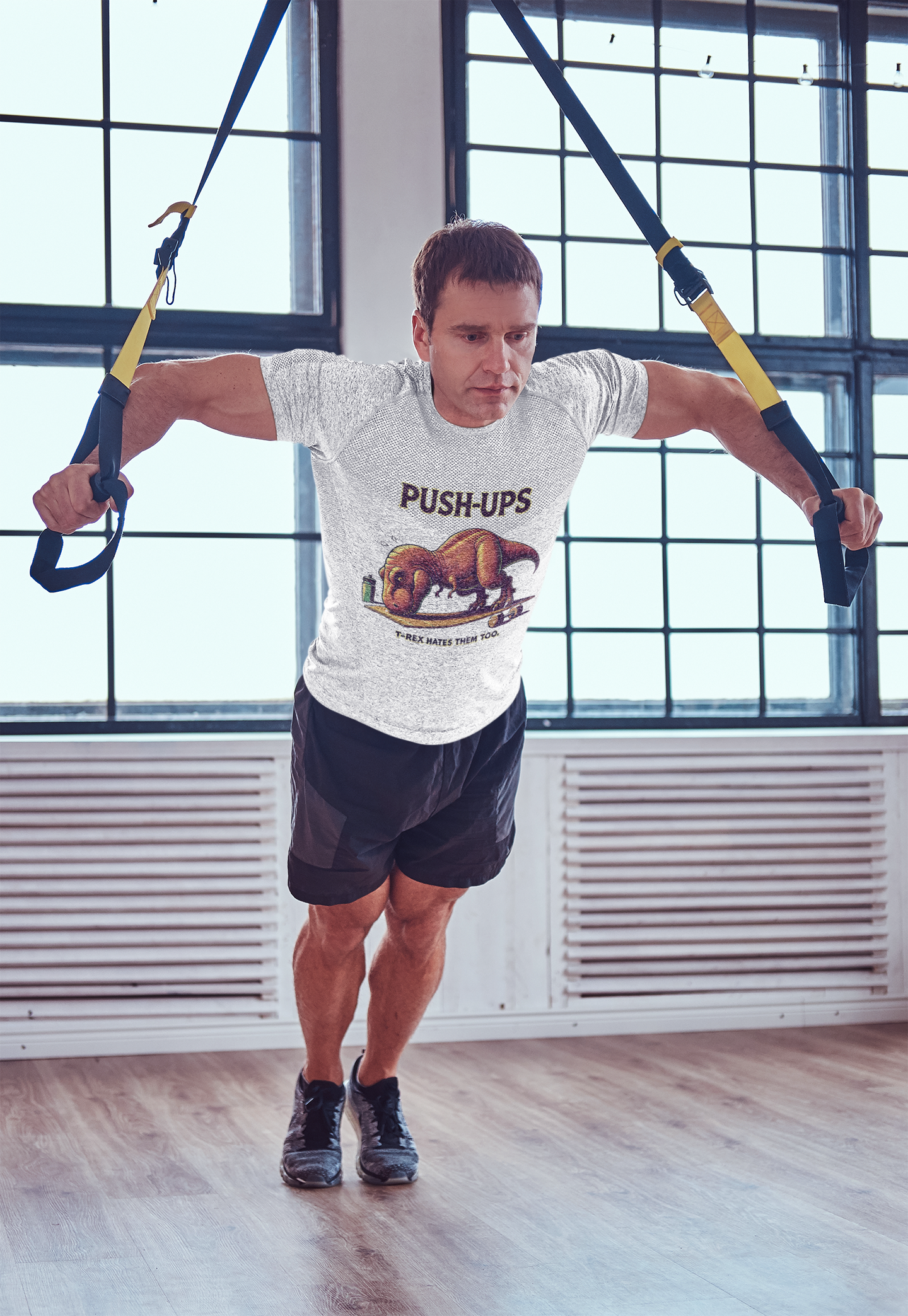 T-Rex Push-Up T-Shirt – Funny Dinosaur Workout Graphic Tee featuring a comical t rex hates push ups design, shown during a TRX workout for fitness lovers.