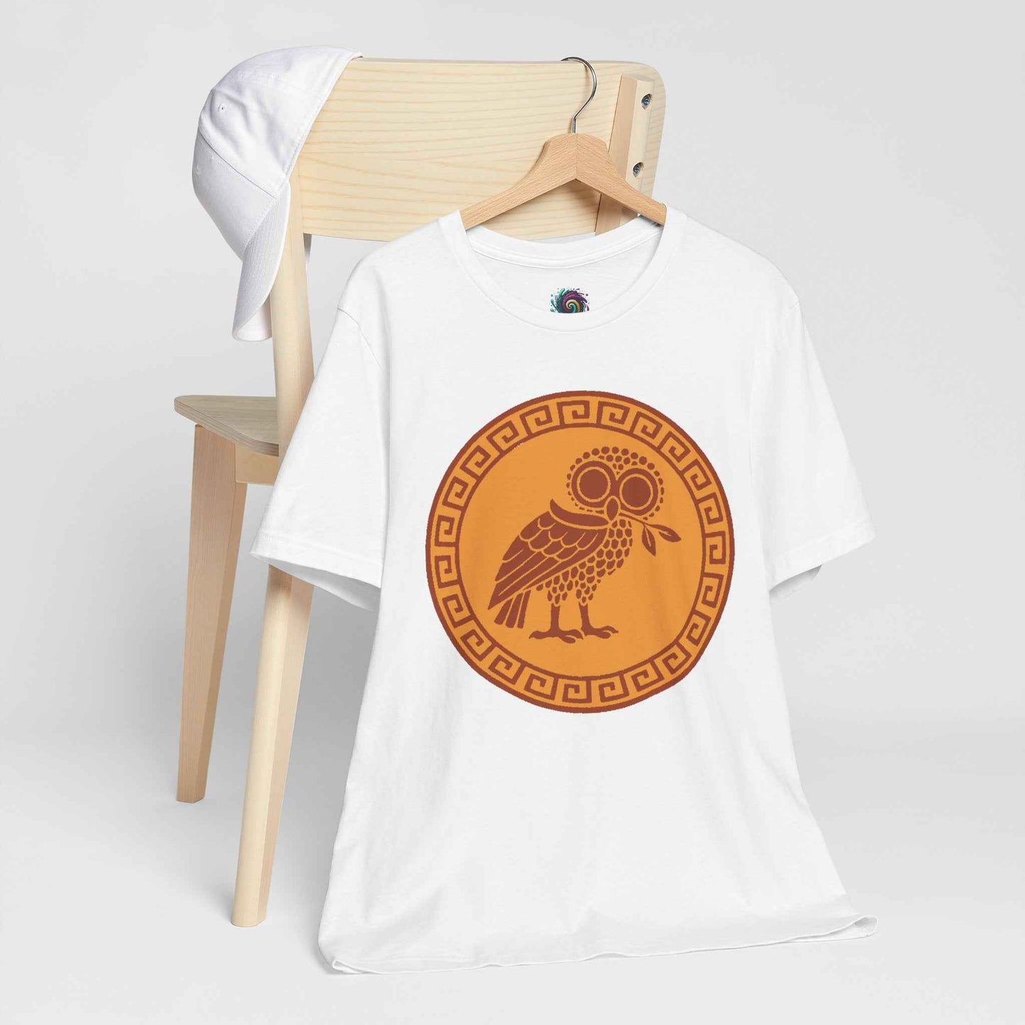 Athena’s Owl T-Shirt – Greek Mythology Bird Tee from Whimspin featuring Athena's bird companion holds an olive branch in her beak in the center of a gold medallion surrounded by a Greek Key motif