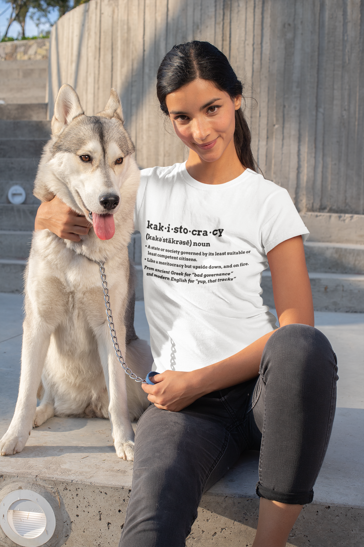 Woman sitting with a dog wearing a white Kakistocracy Definition T-Shirt from Whimspin