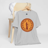 White crewneck T-shirt with circular bronze queen graphic, flat lay on hanger