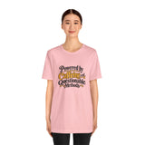 Pink crewneck T-shirt with centered “Powered by Caffeine and Questionable Methods” print.