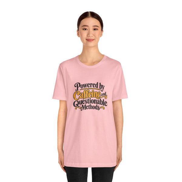 Pink crewneck T-shirt with centered “Powered by Caffeine and Questionable Methods” print.