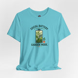 Blue graphic T-shirt flat lay with “SOCIAL BATTERY” and “GARDEN MODE” garden print