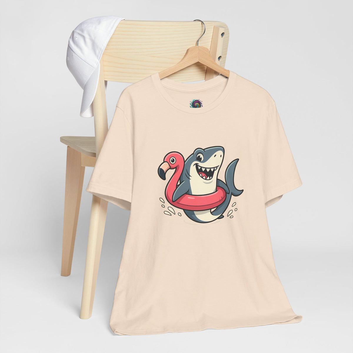 Cream crew-neck t-shirt with colorful shark and flamingo graphic, front view on hanger