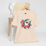 Cream crew-neck t-shirt with colorful shark and flamingo graphic, front view on hanger