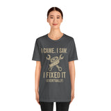 Charcoal short-sleeve tee with centered gold text slogan and crossed tools graphic