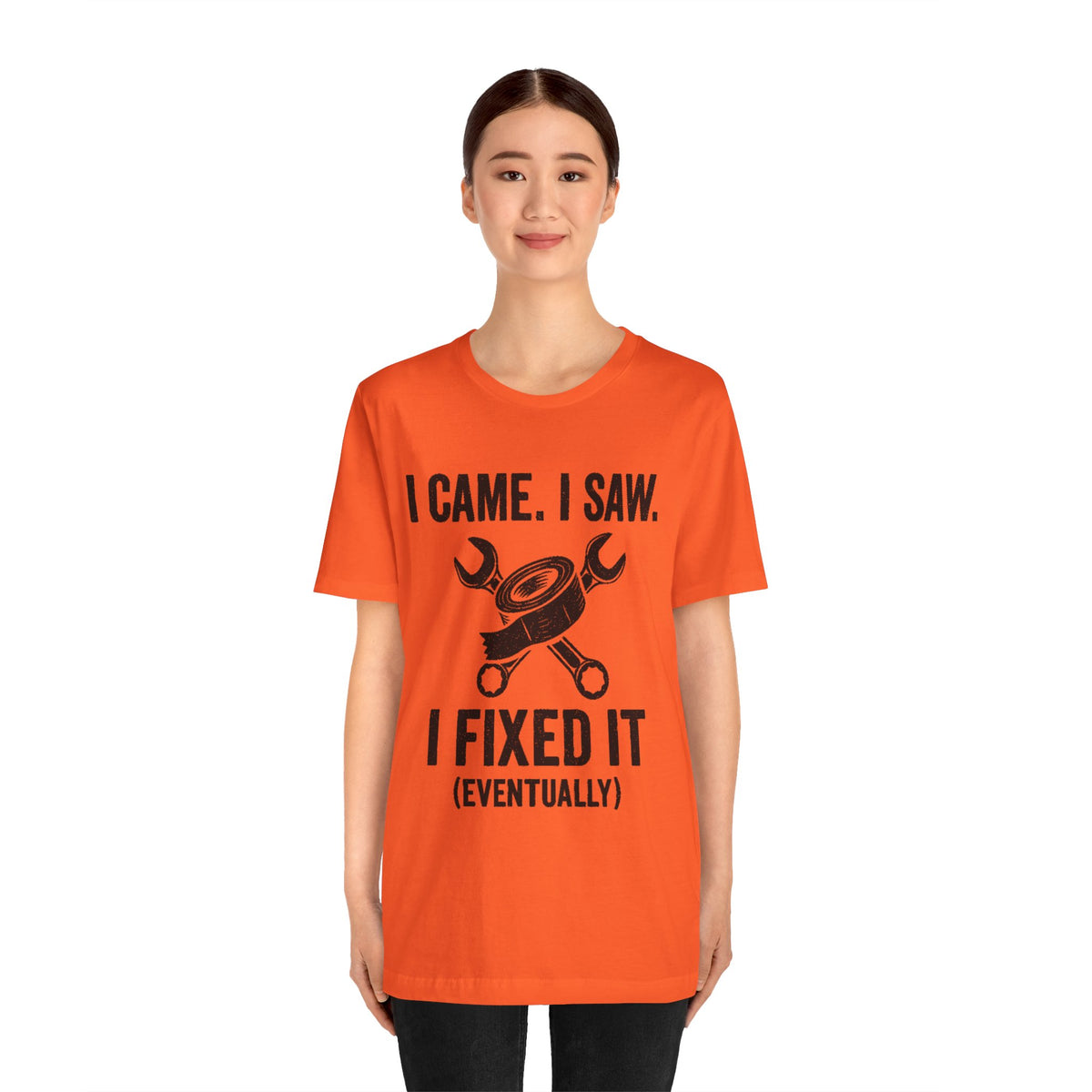 Orange crewneck T-shirt worn by a standing woman, bold repair-themed front graphic