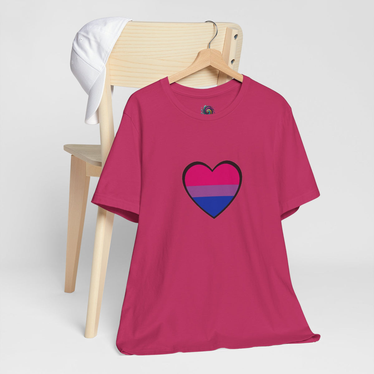 Pink crew-neck T-shirt on hanger with heart graphic in blue and pink pride stripes