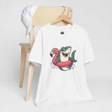 White crew-neck T-shirt with shark-and-flamingo float graphic, hanging on a wooden hanger