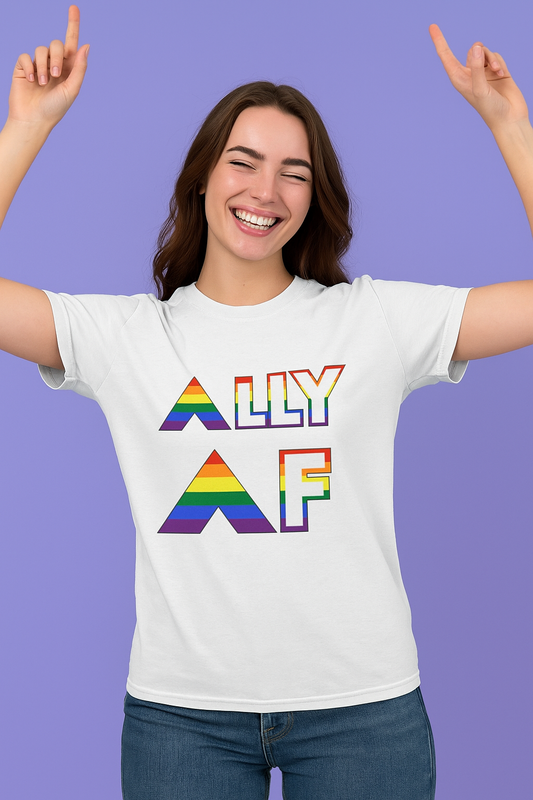 A woman wuth brown hair smiling and raising her hands wearing a white Ally AF shirt that uses rainbow letters.