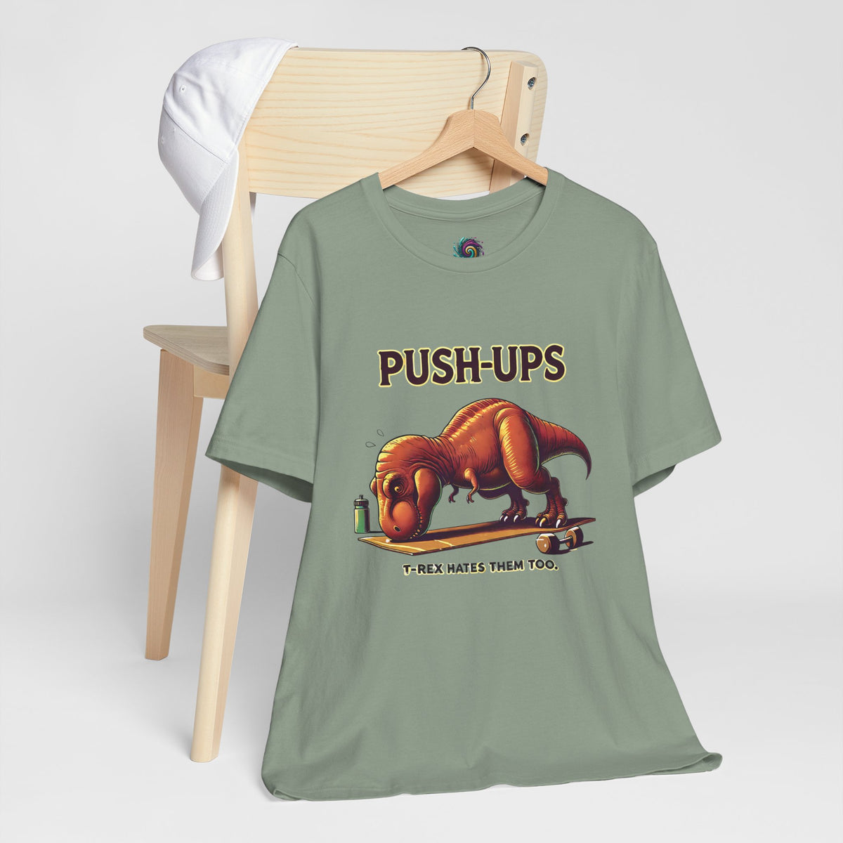 Green graphic T-shirt on hanger with T-rex “Push-ups” workout slogan