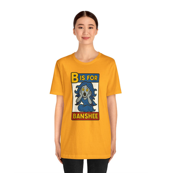 Gold crewneck T-shirt with “B is for Banshee” illustrated character square on front
