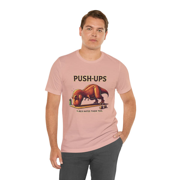 Pink crew-neck T-shirt with “PUSH-UPS” and T-rex workout dinosaur graphic, side pose