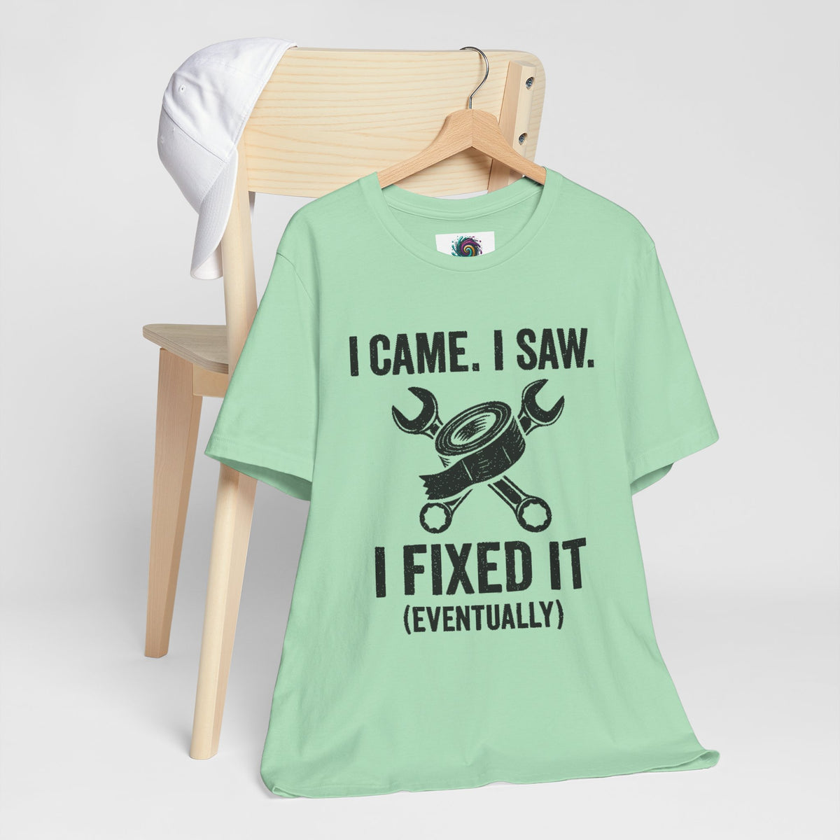 Mint green crew-neck T-shirt on a hanger with black “I fixed it (eventually)” graphic