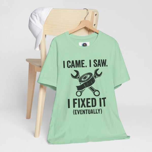 Mint green crew-neck T-shirt on a hanger with black “I fixed it (eventually)” graphic