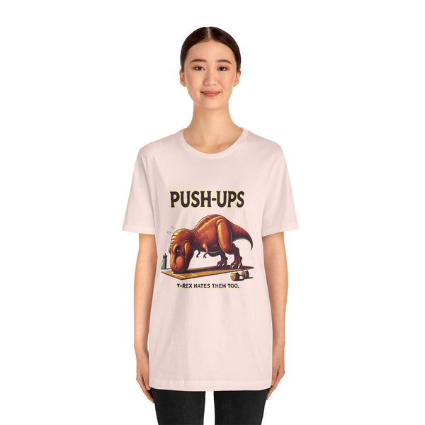 Pink crew-neck graphic tee with “PUSH-UPS” and T-Rex workout graphic