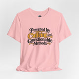 Pink crewneck T-shirt with centered “Powered by Caffeine and Questionable Methods” text graphic.