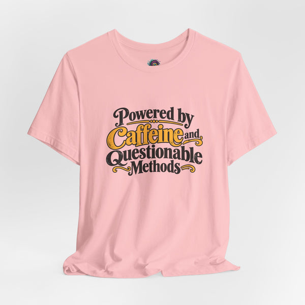 Pink crewneck T-shirt with centered “Powered by Caffeine and Questionable Methods” text graphic.