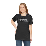 Dark heather grey short-sleeve T-shirt with front graphic text: “Consciousness is an Illusion”.