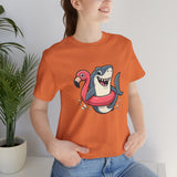 Orange crewneck T-shirt worn by model, shark and flamingo floatie graphic center.