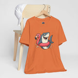 Orange crewneck T-shirt with shark and flamingo floatie graphic on chest.