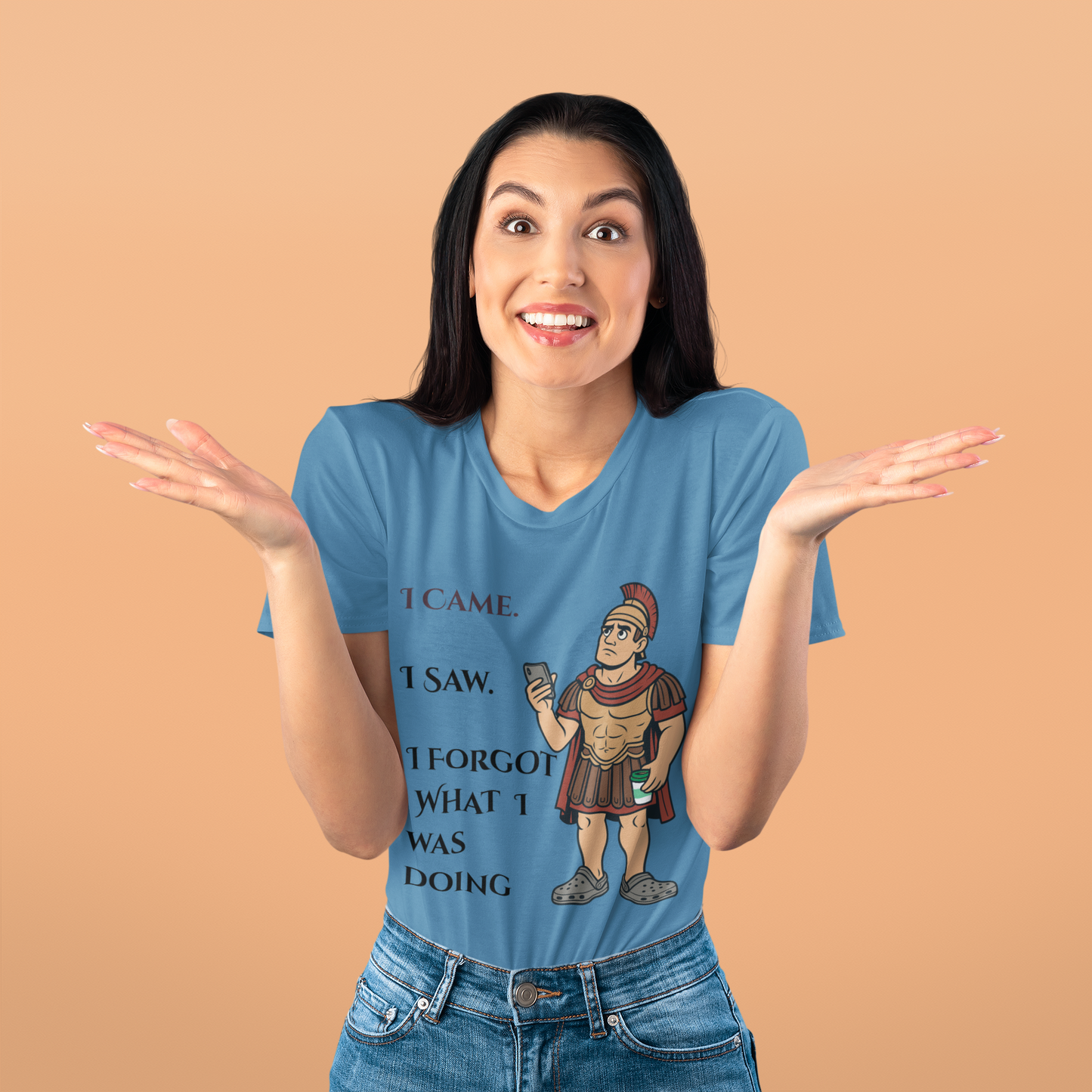 Woman wearing a blue I Am I Saw I Forgot What Was Doing t-shirt from WhimSpin with a graphic and text on a beige background
