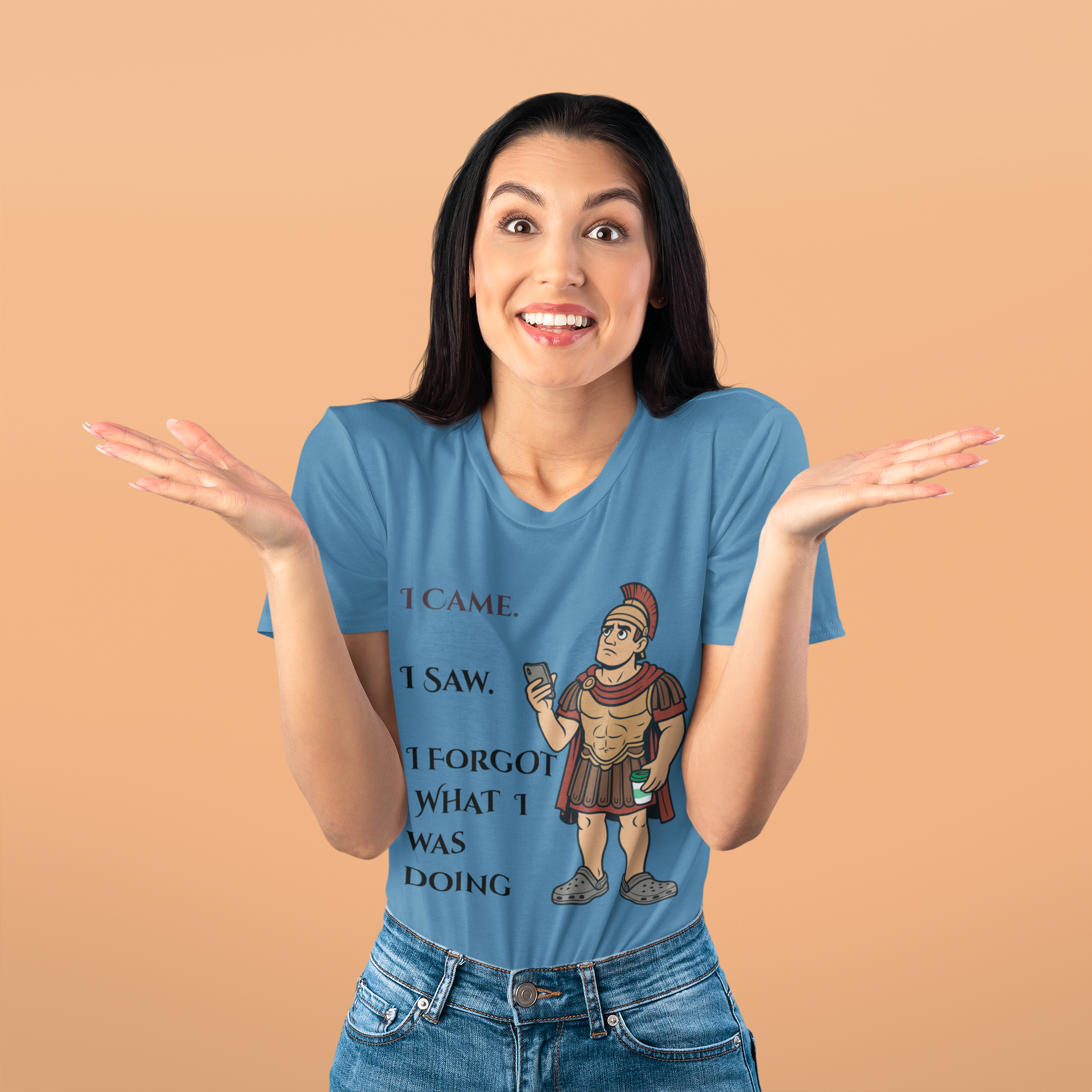 Woman wearing a blue I Am I Saw I Forgot What Was Doing t-shirt from WhimSpin with a graphic and text on a beige background