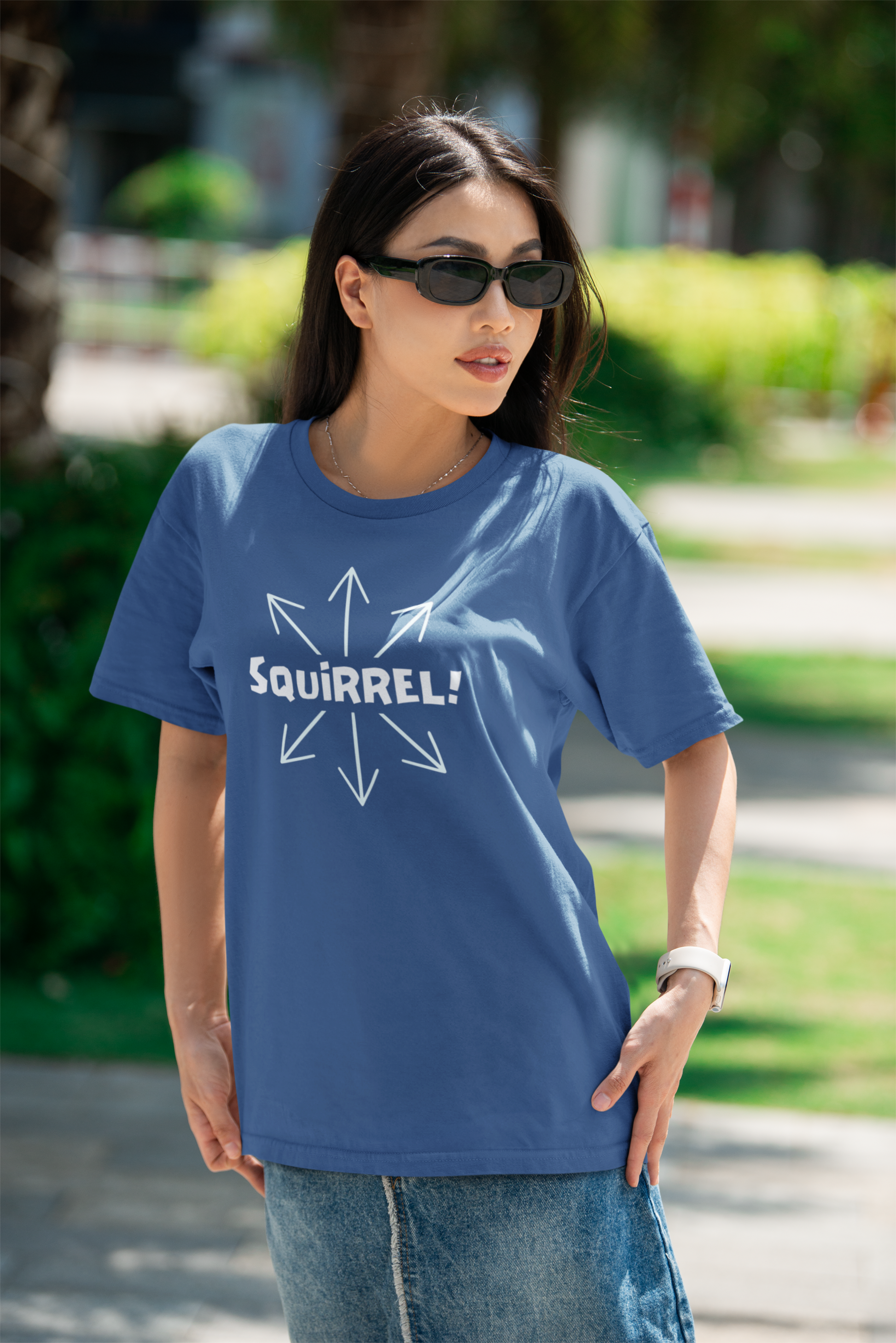 Squirrel Distracted Mind T-Shirt – Funny Attention Graphic Tee woman wear's a columbia blue tshirt word "squirrel" in the center witha rrows pointing in multiple directions. she stands in a park.