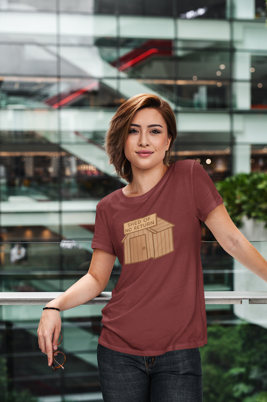 Woman wearing a cardinal red t-shirt with the "shed of no returns" graphic  stands in front of a modern glass building.