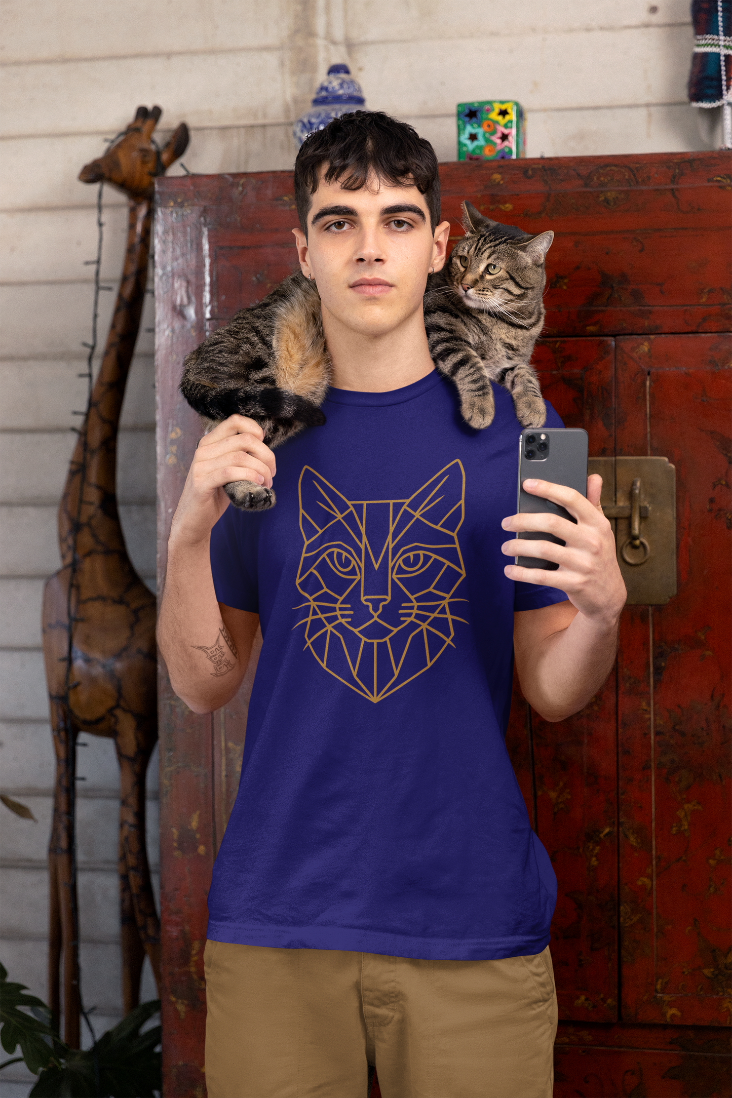 Young man wearing the Geometric Cat T-Shirt – Minimalist Line Art Tee for Modern Cat Lovers in team navy, with a tabby cat perched on his shoulders, emphasizing vector art cats and minimalistic style.