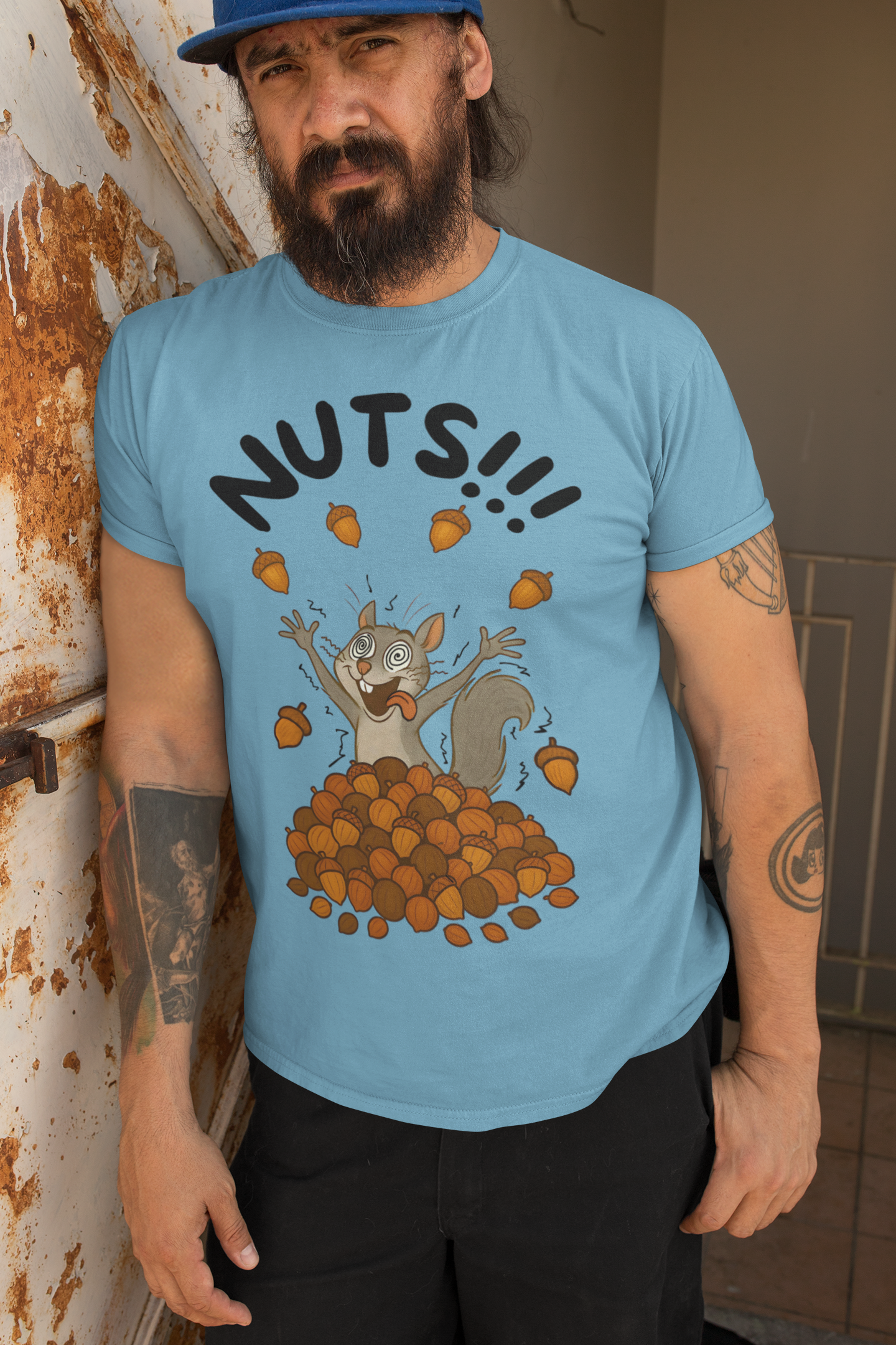 Crazy Squirrel Shirt – Funny Squirrel Nuts T-Shirt for Quirky Style in ocean blue, modeled by a bearded man with tattoos against rustic wall