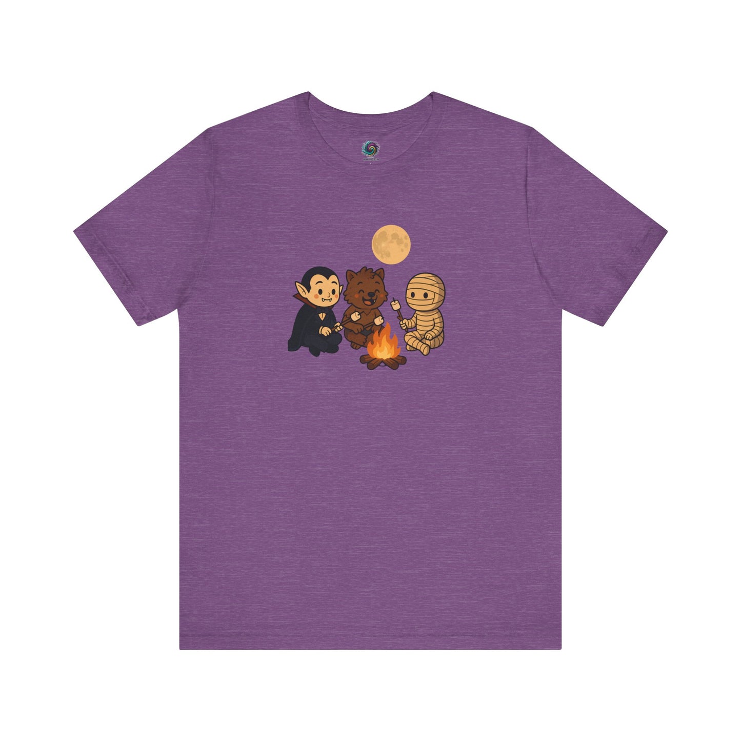 Flat lay of the Heather Team Purple Halloween Monsters Campfire T-Shirt featuring a whimsical Halloween campfire scene with a smiling vampire, werewolf, and mummy toasting marshmallows.