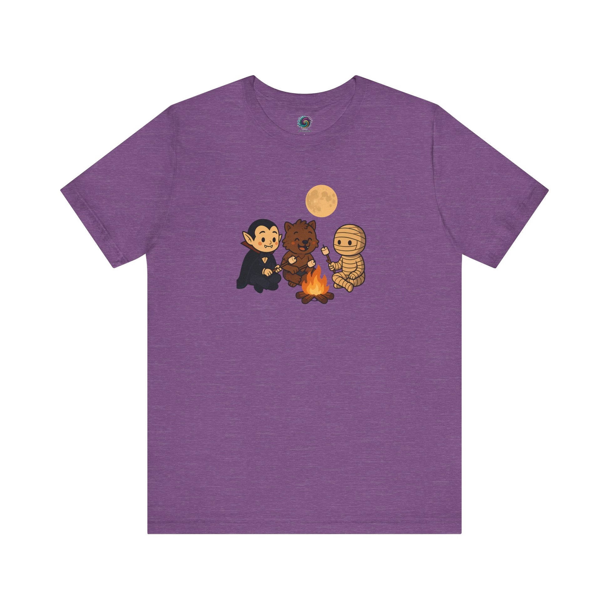 Flat lay of the Heather Team Purple Halloween Monsters Campfire T-Shirt featuring a whimsical Halloween campfire scene with a smiling vampire, werewolf, and mummy toasting marshmallows.