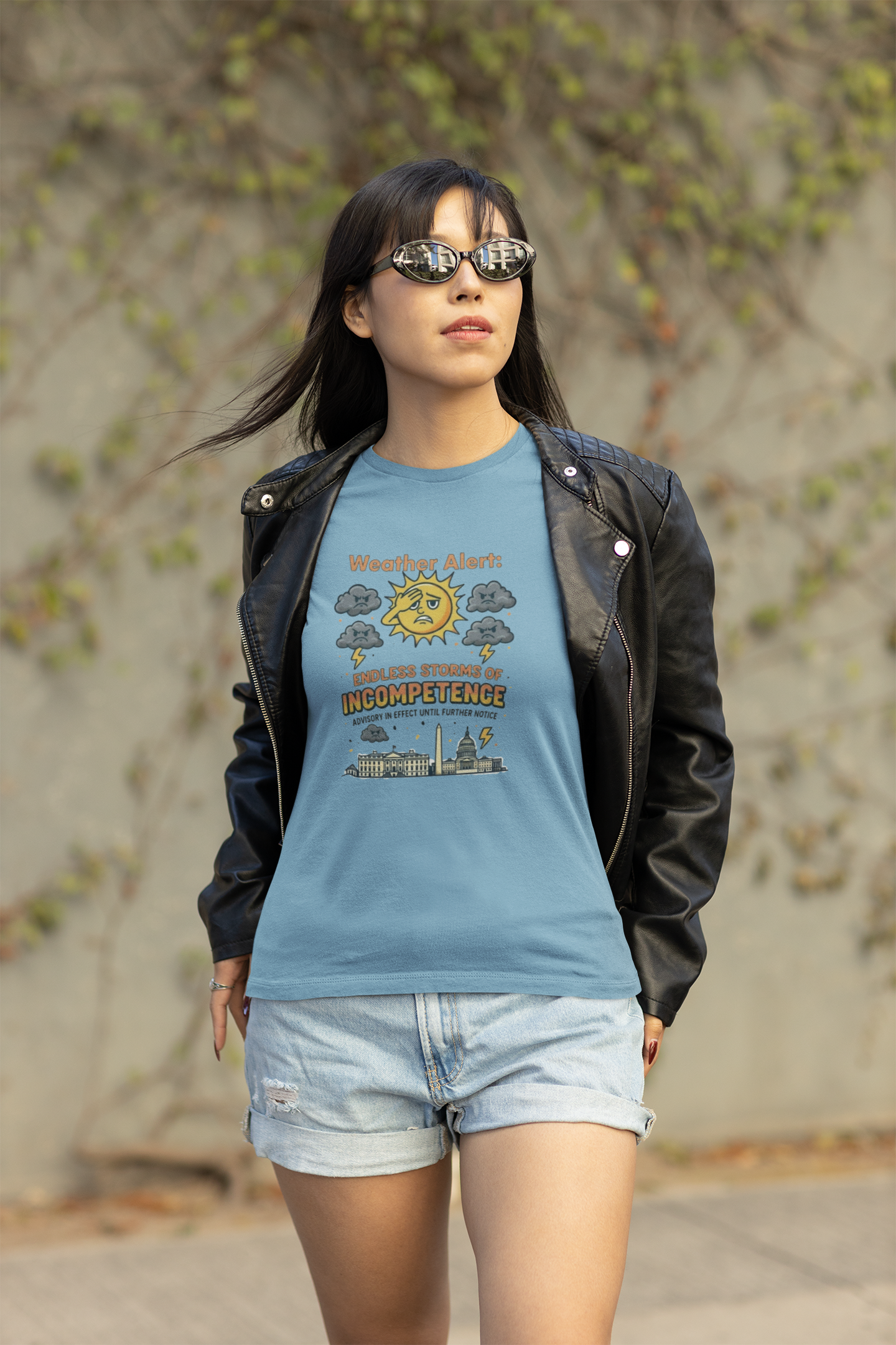 A woman in sunglasses and a leather jacket walks confidently wearing the Weather Alert: Endless Storms of Incompetence Political Satire T-Shirt in ocean blue. Satirical design with sun, lightning, and D.C. landmarks.