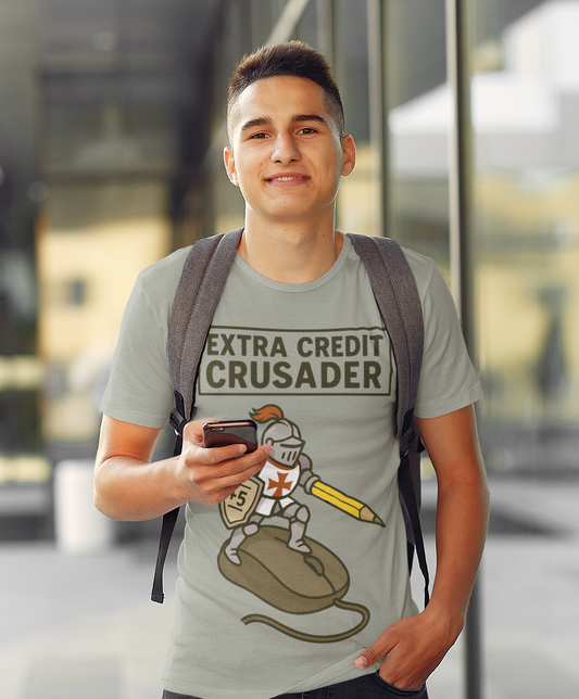 A college aged man wear a grey Extra Credit Crusader T-Shirt from WhimSpin. The tshirt graphic features a knight templar riding a computer mouse, with a giant pencil under his arm like a lance, and carrying a shield with "+5" written on it. 