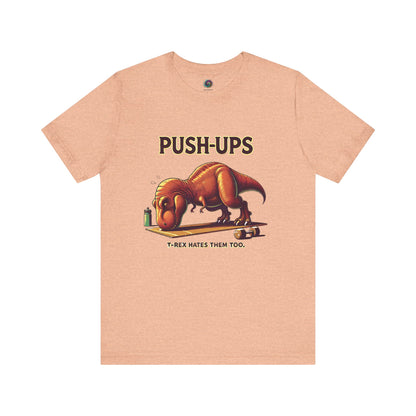 T-Rex Push-Up T-Shirt – Funny Dinosaur Workout Graphic Tee in heather peach, showcasing a goofy t rex push up design great for fitness motivation.