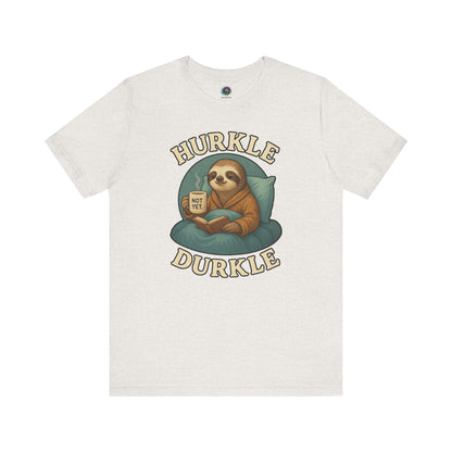 Hurkle Durkle Sloth T-Shirt – Cozy Sloth Shirt for Lazy Days laid flat in Heather Cement featuring a sloth, book, and warm beverage
