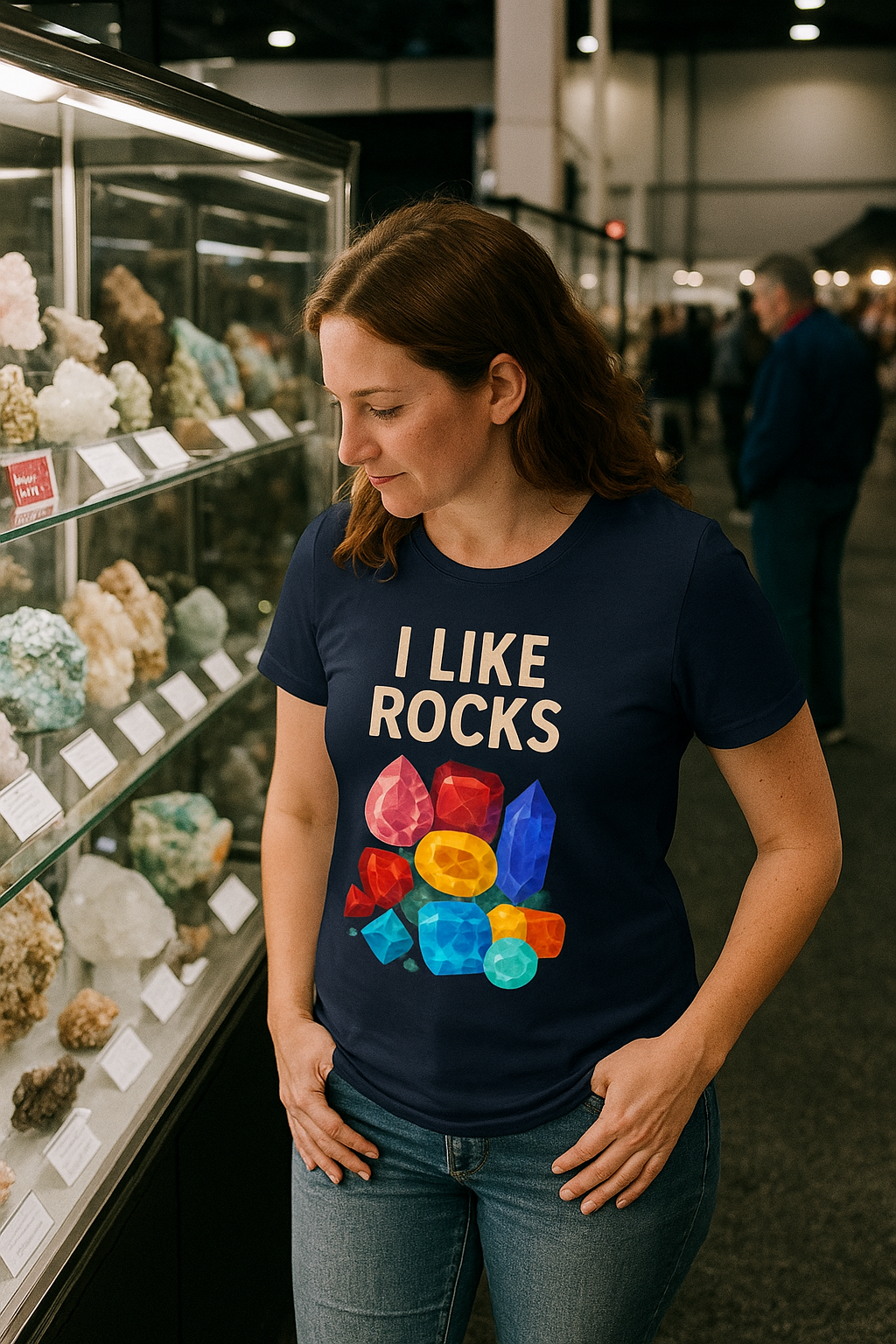 Woman in I Like Rocks Shirt admiring minerals at a rock show exhibit, navy shirt with vibrant gem shapes, ideal for geology fans or i like rocks meme enthusiasts.