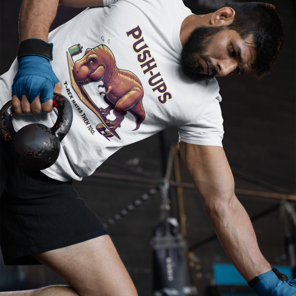 T-Rex Push-Up T-Shirt – Funny Dinosaur Workout Graphic Tee with t rex workout theme, worn mid-kettlebell routine by muscular athlete.