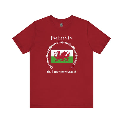 Llanfairpwllgwyngyllgogerychwyrndrobwllllantysiliogogogoch T-Shirt – Funny Wales Travel Merch in canvas red with bold white lettering and centered Welsh flag graphic.