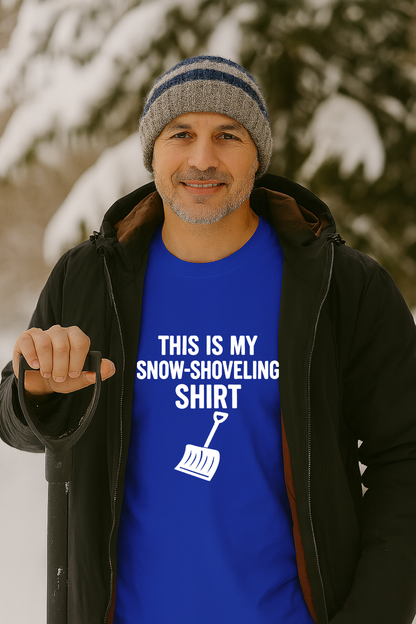Image of a man standing outdoors in winter holding a snow shovel while wearing the This Is My Snow Shoveling Shirt – Funny Winter Chore Tee, with bold white text and shovel graphic against a snowy background.