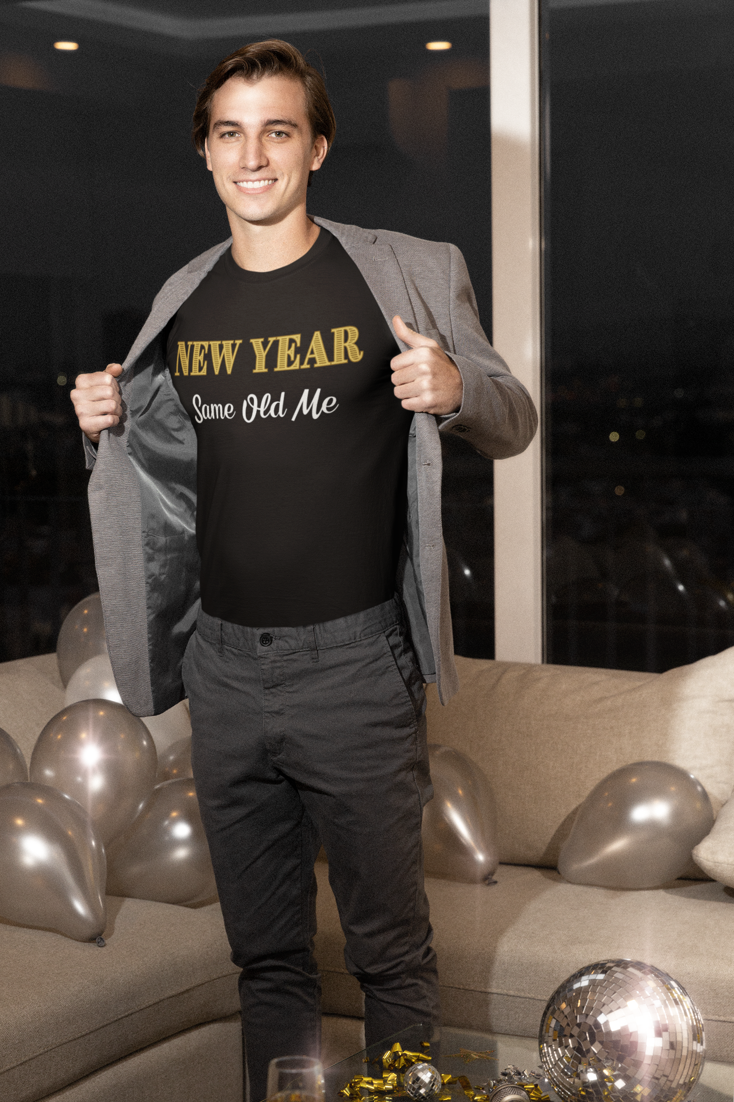 Image of a man wearing the New Year Same Old Me T-Shirt – Funny Self-Confidence Tee under an open blazer, standing in a decorated living room with balloons and party decor.