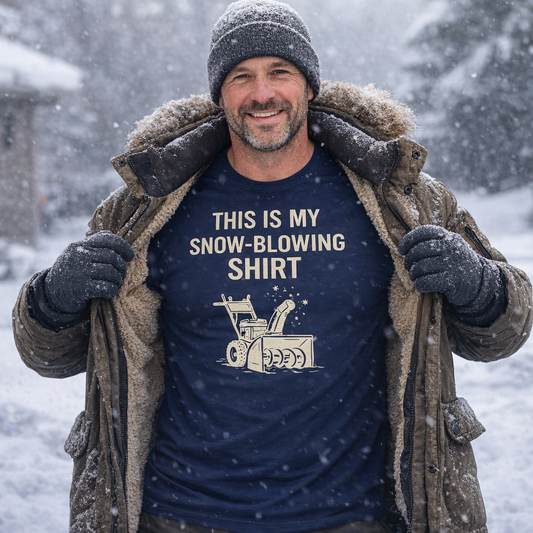 Image of a man outdoors in falling snow wearing the This Is My Snow-Blowing Shirt – Funny Winter Chore Tee, holding open a winter jacket to reveal the snow blower graphic and bold winter message.